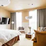 Et stilfuldt hotelværelse på Hernö Gin Hotel med en stor seng, en hyggelig sofa og lyse vinduer, designet til afslapning.