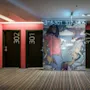 301 and 302 doors flank a mural of a person in a pink shirt with bullets. Striped carpet lines the floor. 