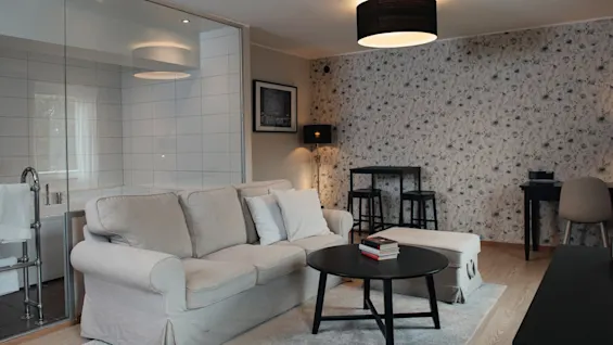 A welcoming living space with a comfortable sofa, coffee table, and a work area, next to a bright, modern bathroom.