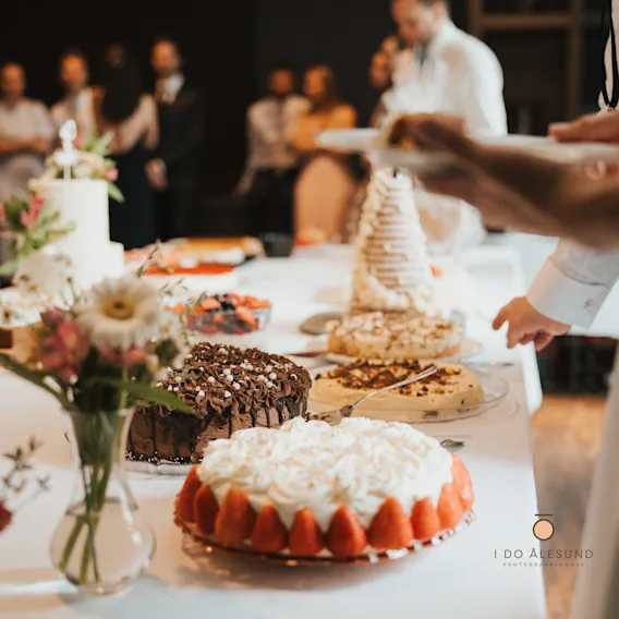 Et bryllupskakebord anrettet med ulike kaker, inkludert jordbærkake og sjokoladekake.