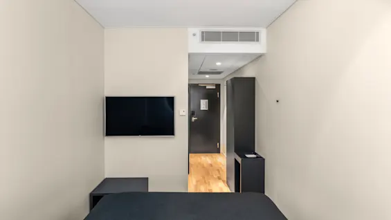 Et moderne og indbydende hotelværelse med en komfortabel seng, et vægmonteret tv og en klar vej til døren.