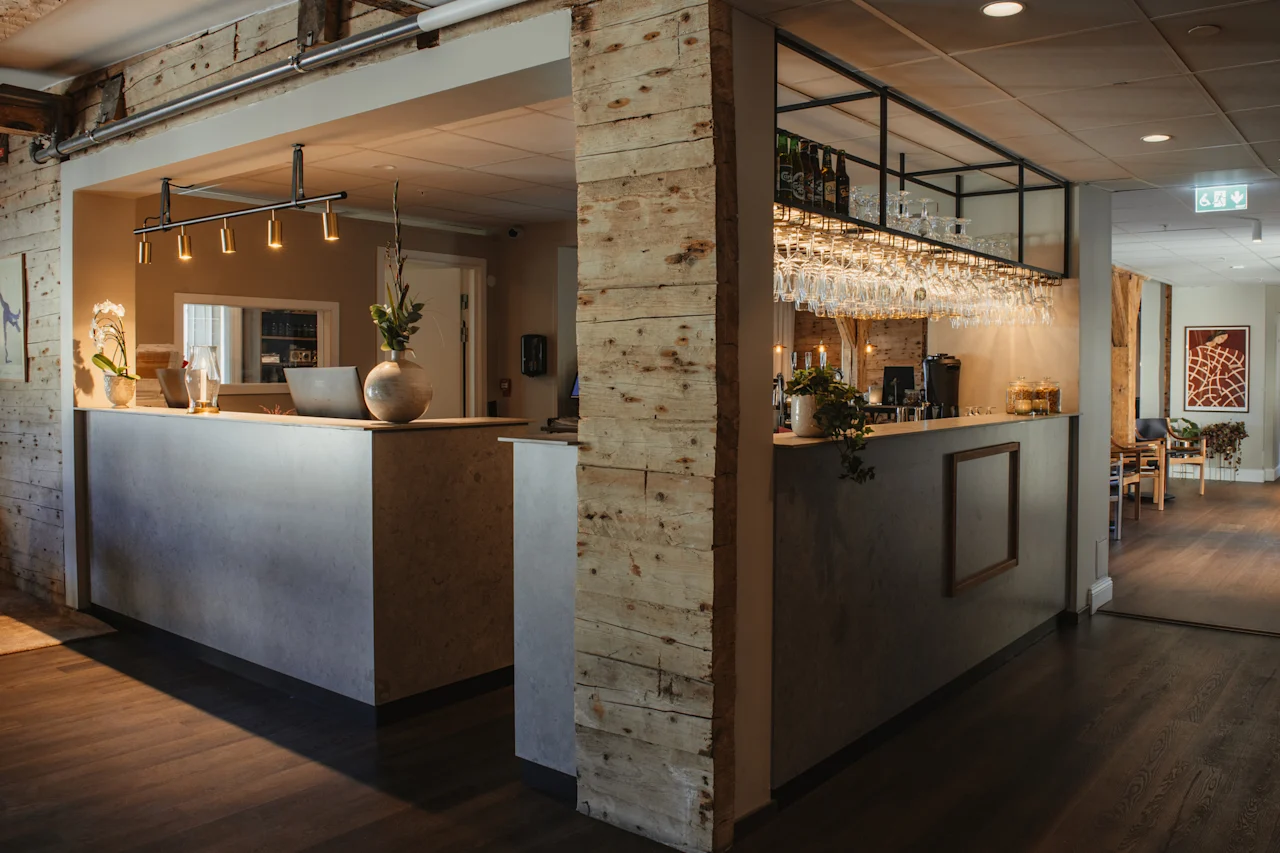 En moderne og indbydende hotellobby med reception og bar, med varm belysning og naturligt træ.