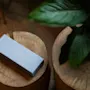 A light blue box with the word DOMINO on it rests on a wooden surface next to a green plant.