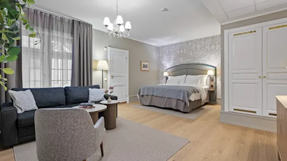 Et stilfuldt hotelværelse med en komfortabel seng, en hyggelig sofa og en lænestol, perfekt til afslapning.