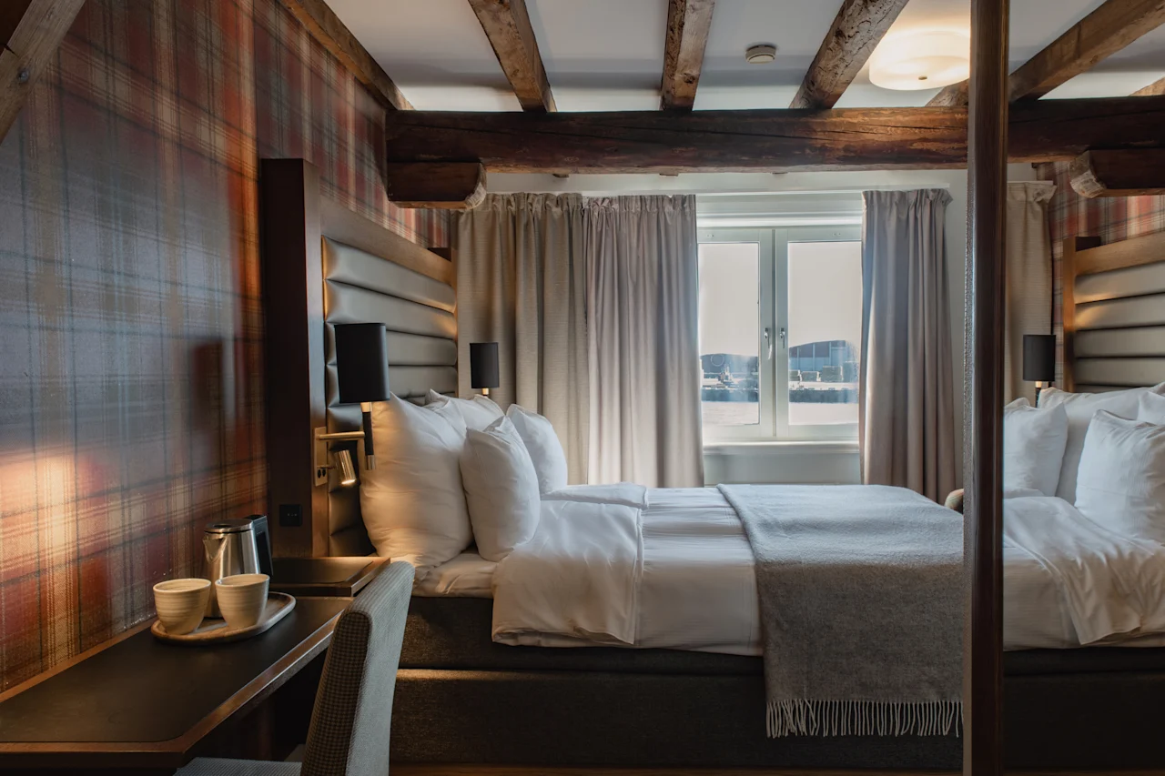 Et indbydende hotelværelse med en komfortabel seng, en varmternet væg og en naturskøn udsigt over vandet.