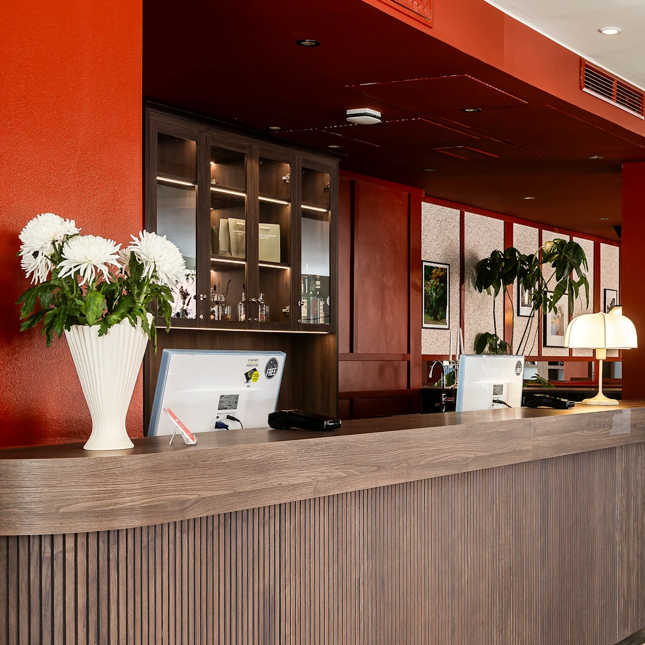 Ett tomt hotellreceptionsområde med trädisk, stolar, dekorativa växter och varmt ljus.