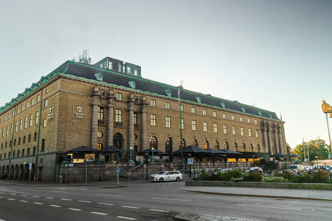 Exteriör vy av Clarion Hotel Post, en ståtlig byggnad med grönt tak och uteserveringar, intill en gata.