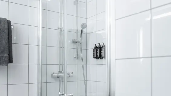 A bright, tiled shower area with a shower head and wall-mounted toiletries, ready for a refreshing wash.