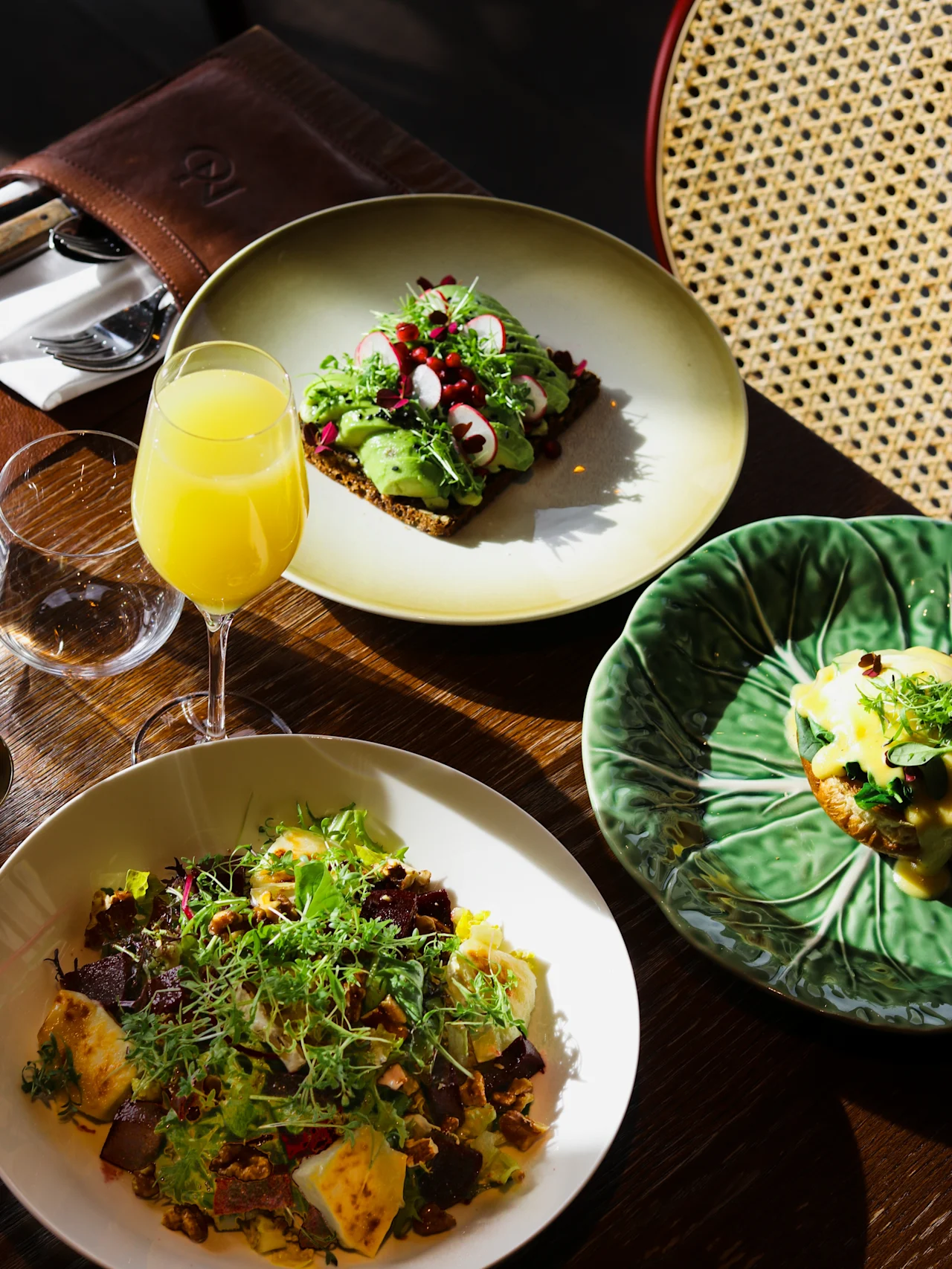 Et bord dekket med en fargerik frokost eller brunsj, inkludert avokadotoast, en frisk salat og eggs benedict.