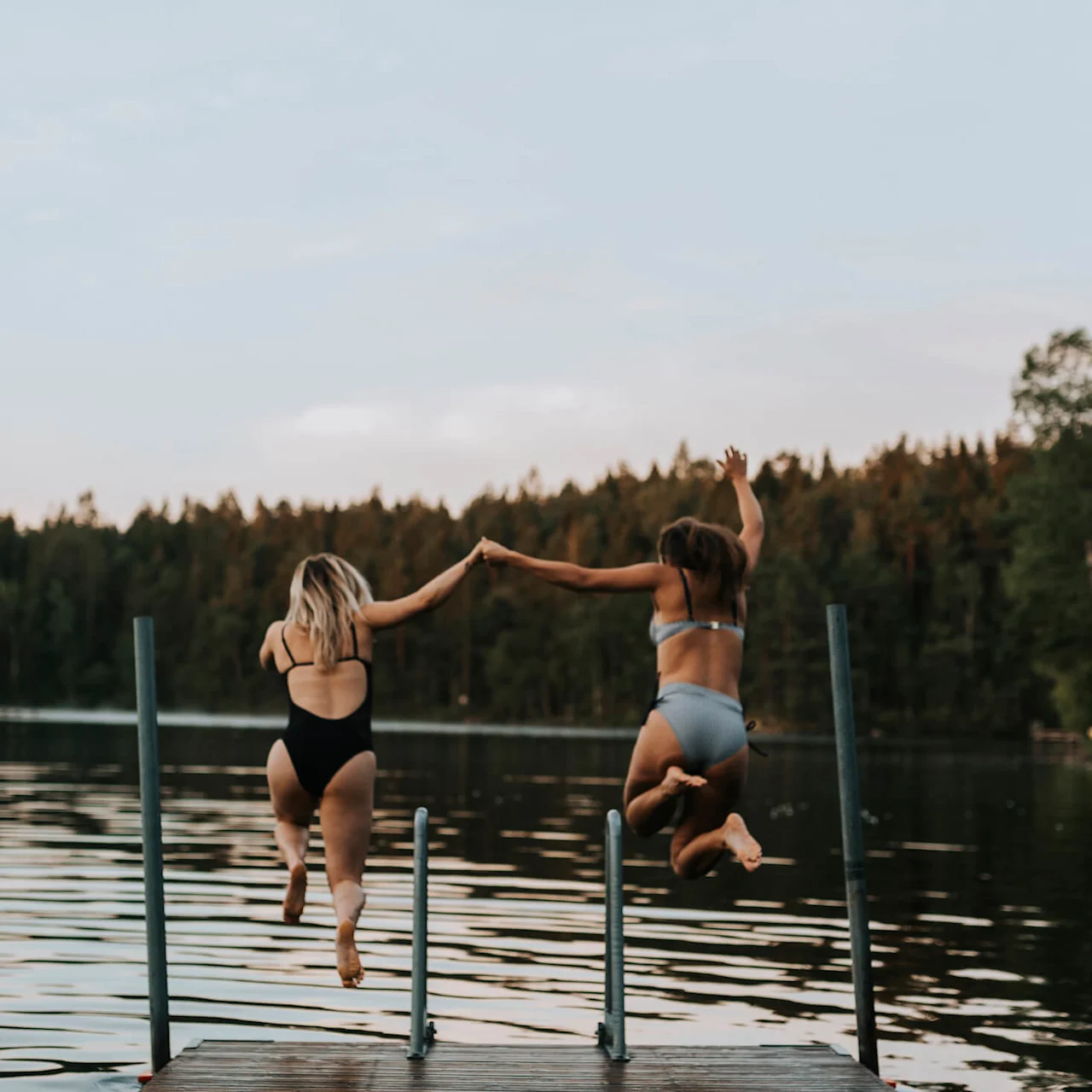 Two women jumping into a Swedish lake in summer - the real Nordic holiday feeling