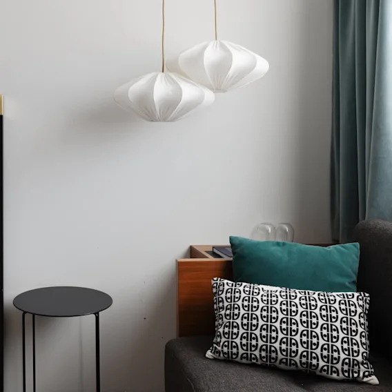 En pænt redt seng med et sidebord og hængende lys; en moderne soveværelsesindretning.