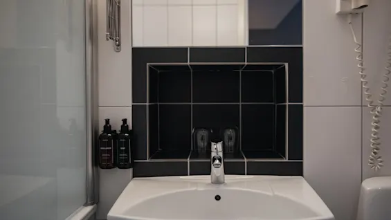 Ett välutrustat hotellbadrum på Home Hotel Grand, Helsingborg, med handfat, spegel och tillgänglig BODY LOTION och SOAP.