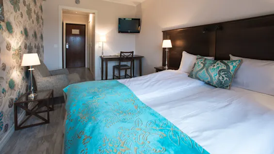 Ett prydligt hotellrum med en säng och en sittgrupp, visar en välkomnande atmosfär med dekorativa element.