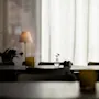 Rauhallinen ja kutsuva ravintolan sisustus, jossa pöydät on katettu ruokailua varten, valaistuna pehmeällä luonnonvalolla.