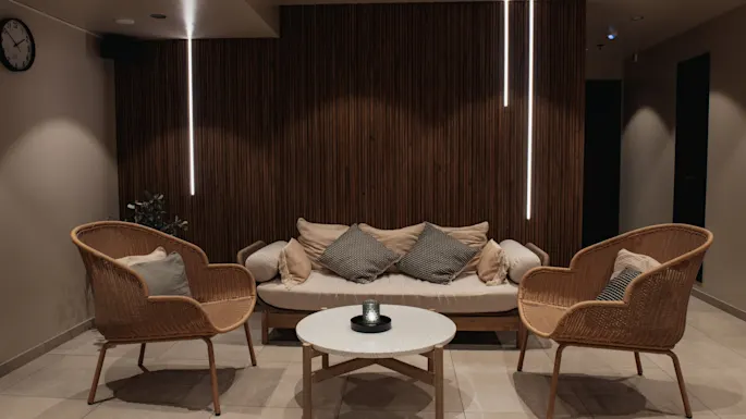 Et koselig salongområde på Home Hotel Uppsala med en sofa, to lenestoler og et salongbord, med varm belysning og en aksentvegg i tre.