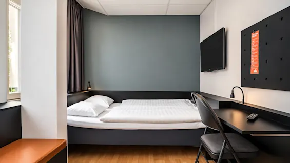 Modern hotel room featuring a double bed, desk, and chair