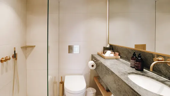 Ett modernt och rent badrum med dusch, vägghängd toalett och en stilren handfatsdel.