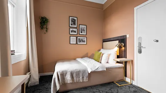 Et innbydende hotellrom på Home Hotel Gabelshus med en komfortabel seng, varme ferskenfargede vegger og et mønstret gulv.