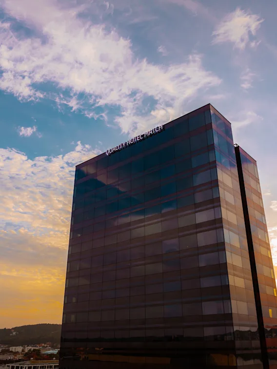 A tall modern hotel building standing against a beautiful sunset sky with soft clouds