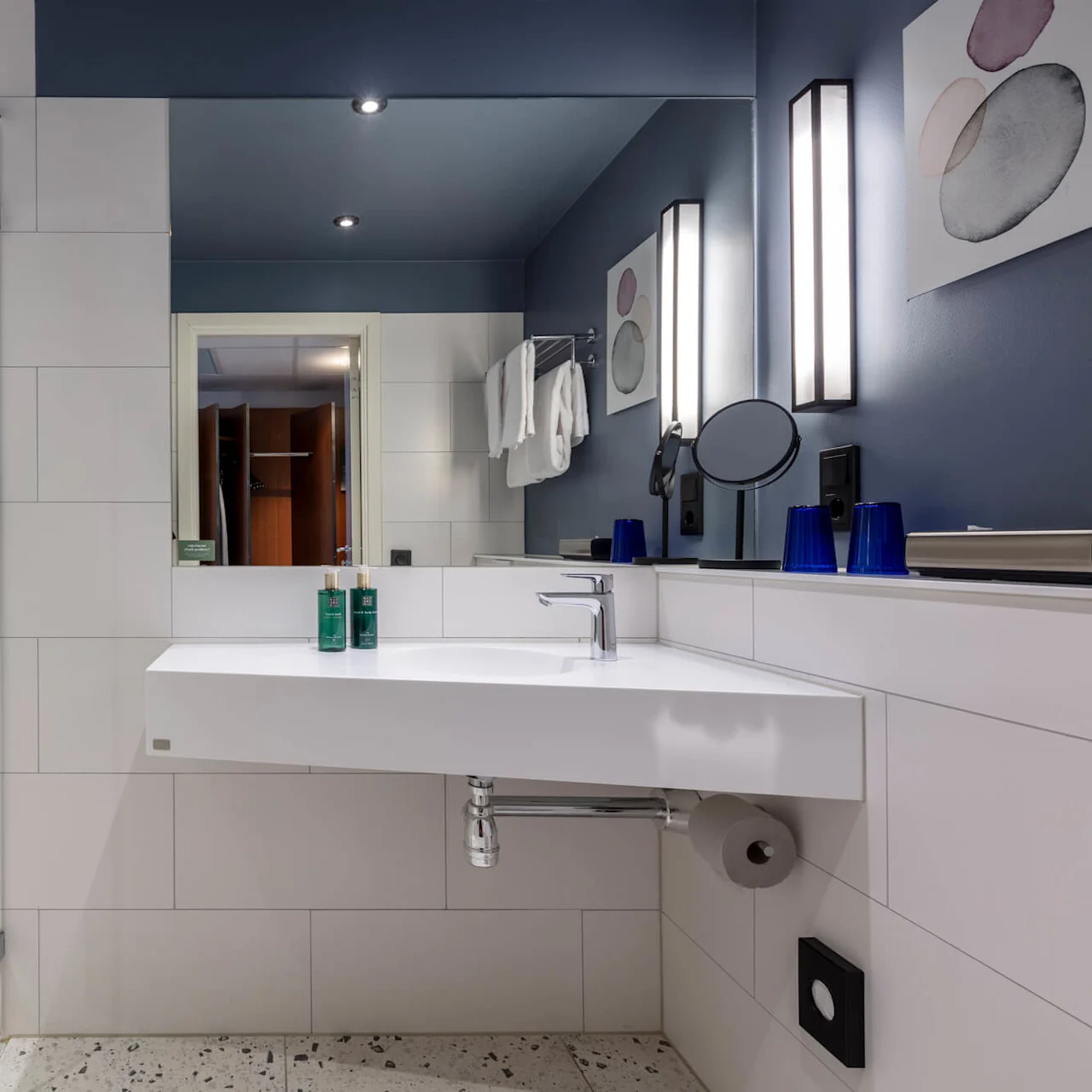 Modern bathroom interior with a floating vanity, mirror, shower area, and blue accents within a home setting.