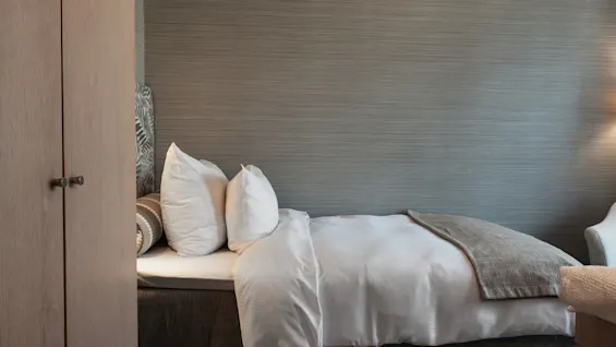 Et hyggeligt hotelværelse på Home Hotel Wellington med en redt seng, hvide puder og et gråt tæppe.