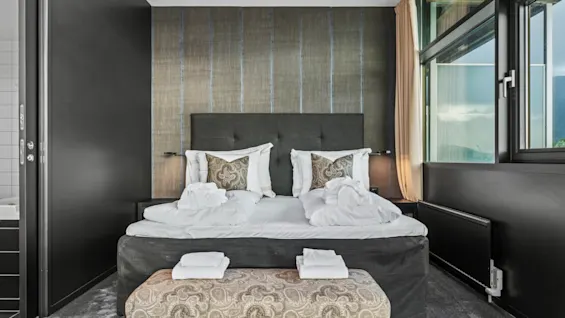 Et koselig hotellrom på Quality Hotel Ulstein med en stor seng, badekåper og en naturskjønn utsikt fra vinduet.