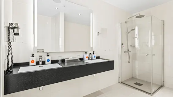 Modernt badrum på Quality Hotel Ulstein med dubbelhandfat, stor spegel och glasdusch för en uppfriskande vistelse.