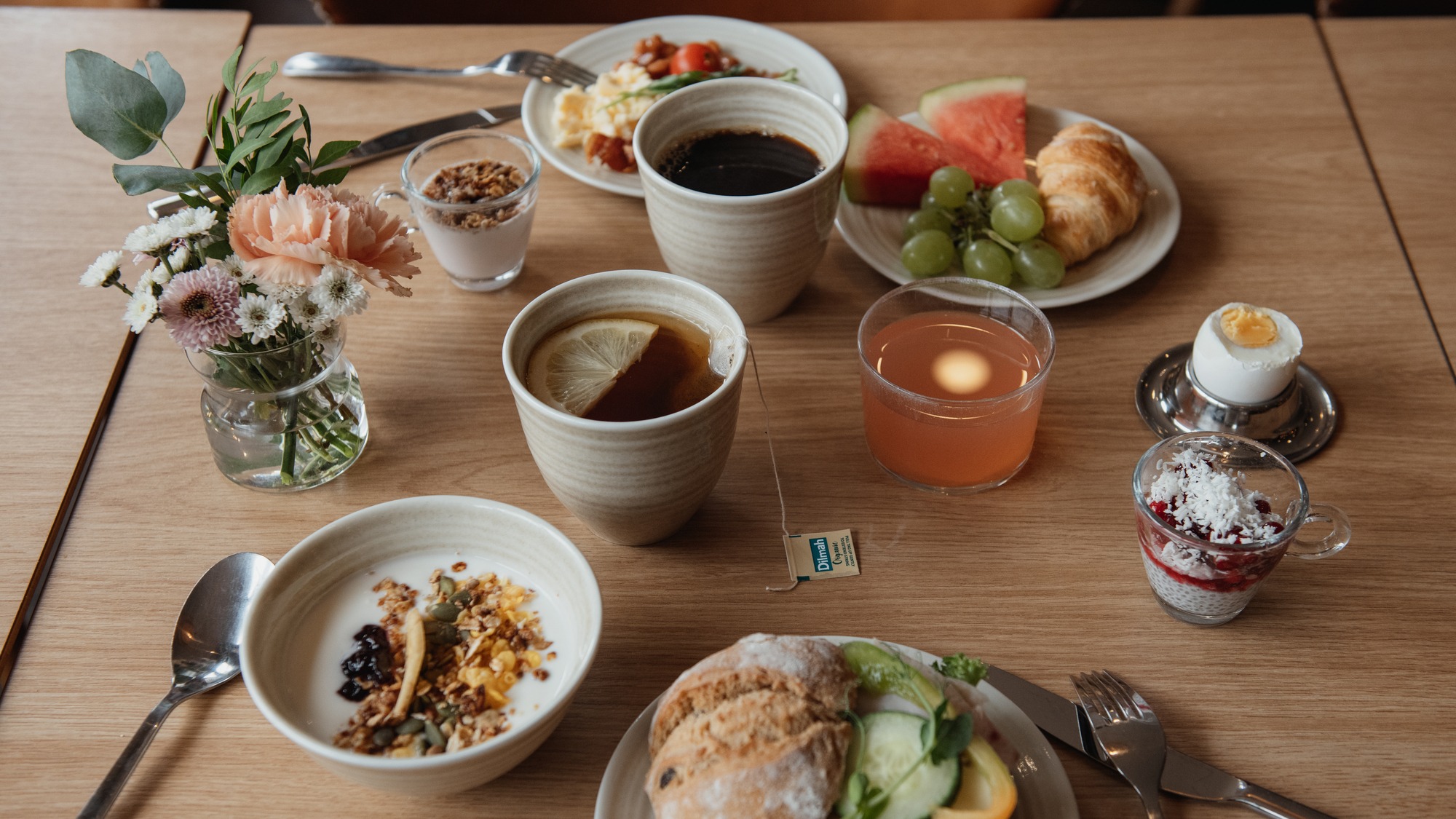 Ett bord dukat med en härlig frukostbuffé inklusive kaffe, te, juice, bakverk, frukt och salta rätter.