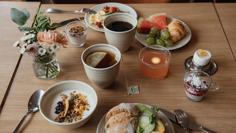 Et bord dækket med en dejlig morgenmadsbuffet inklusive kaffe, te, juice, bagværk, frugt og salte retter.