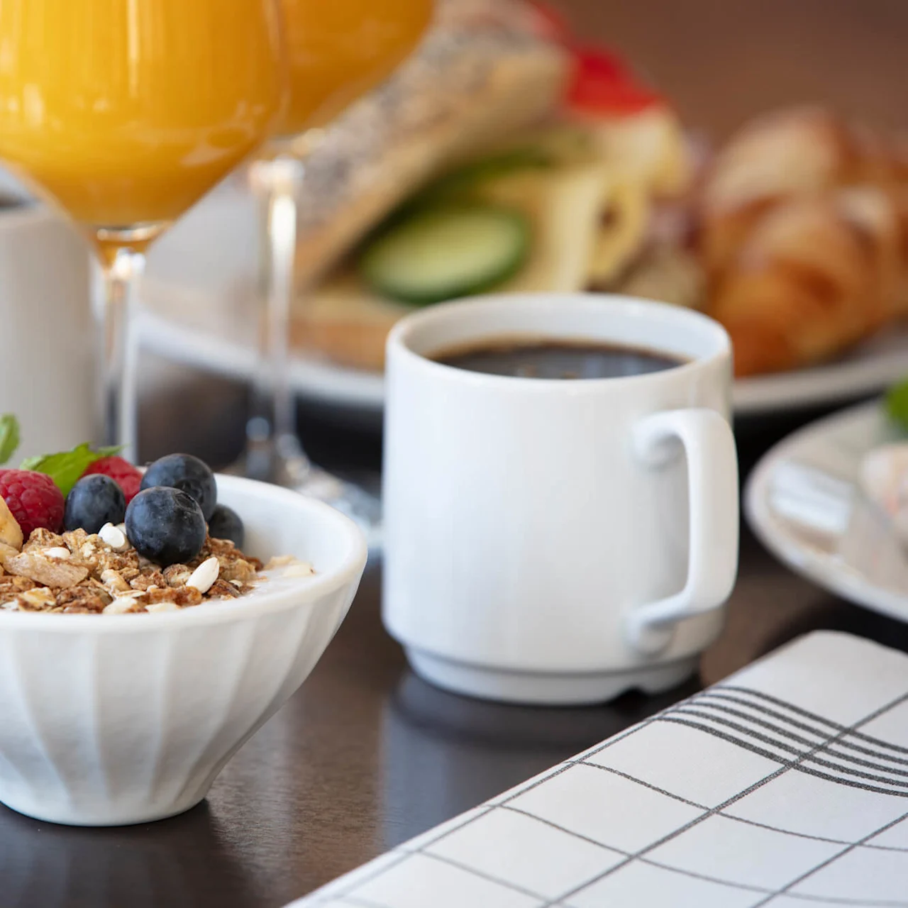 A breakfast setup with cereal, fruit, egg, coffee, and juice on a table.