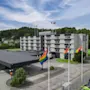 Ett fler våningshotell har regnbågsflaggor vid ingången, omgiven av träd och kullar. Text: "Quality Hotel."