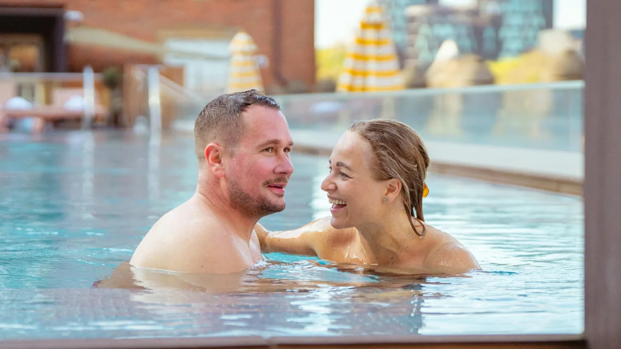 Two people laughing in the rooftop pool at hotel Villa Copenhagen.