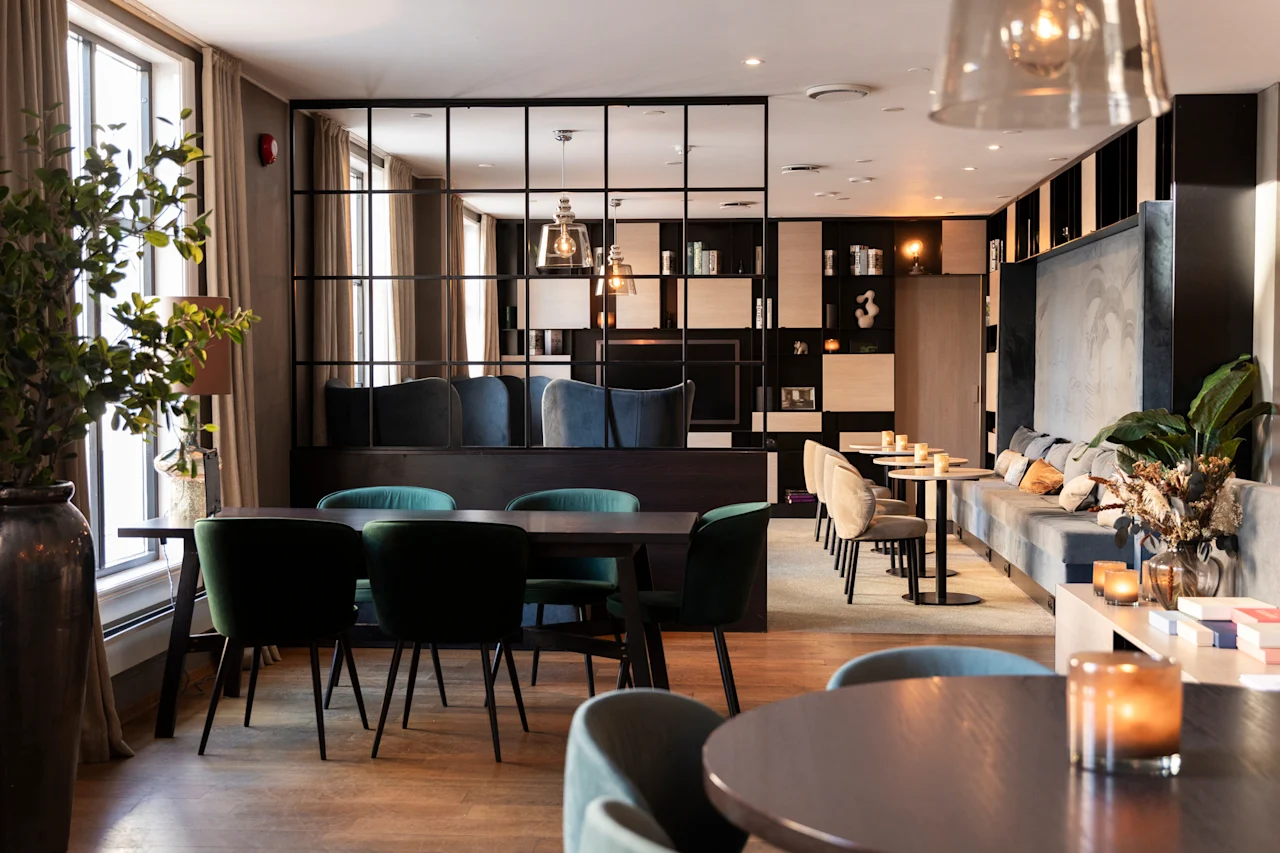 Et stilfuldt og indbydende loungeområde med forskellige siddepladser, herunder spiseborde, komfortable stole og en lang sofa.
