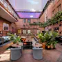 An inviting indoor courtyard at Comfort Hotel Vesterbro with dining tables, lush plants, and brick walls under a bright skylight.