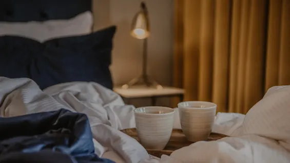En mysig hotellsäng med två koppar på en bricka, redo för en avkopplande stund på Home Hotel Grand, Helsingborg.