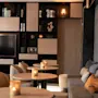 Et hyggeligt loungeområde med et stort tv, hylder fyldt med bøger, små borde med tændte stearinlys og en komfortabel sofa.