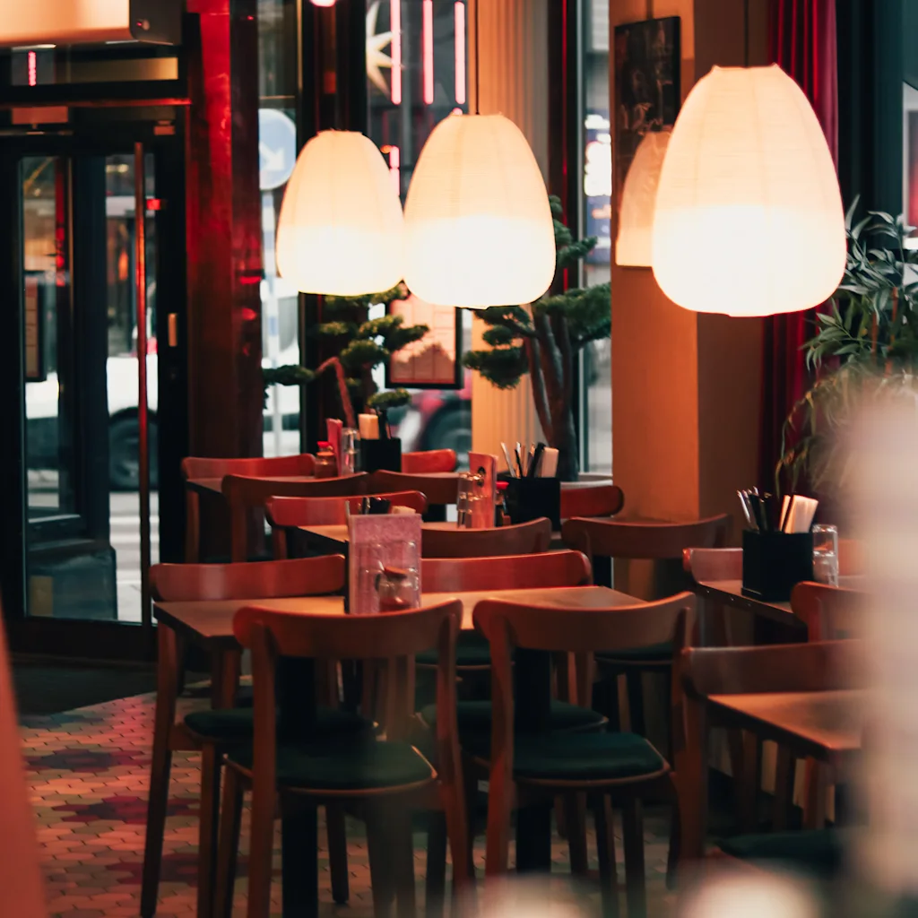 Hyggeligt interiør af Restaurang Tao Noi med varm belysning, træborde og stole, der skaber en indbydende atmosfære.