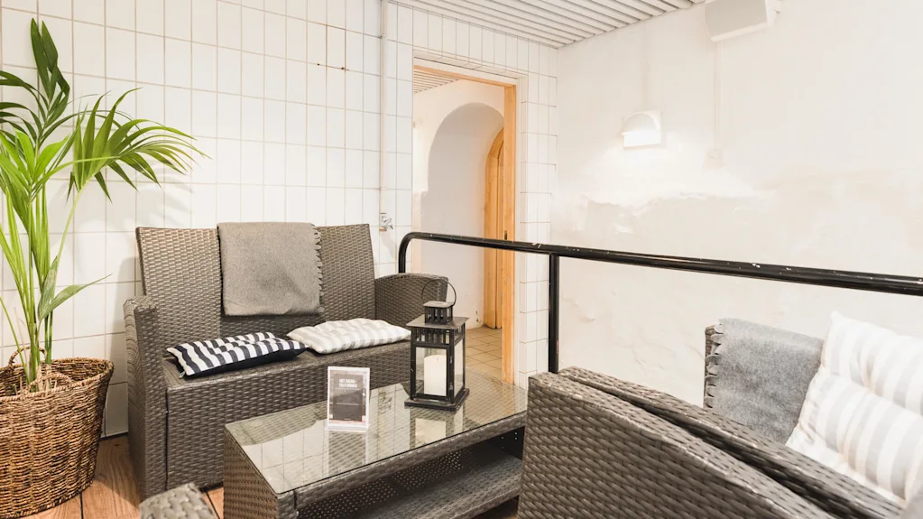 A cozy, indoor lounge area with wicker furniture and a plant, suggesting relaxation in a casual setting.