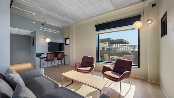 Deluxe-rom på Comfort Hotel Porsgrunn med et moderne oppholdsrom, med sofa, lenestoler og skrivebord, badet i naturlig lys.