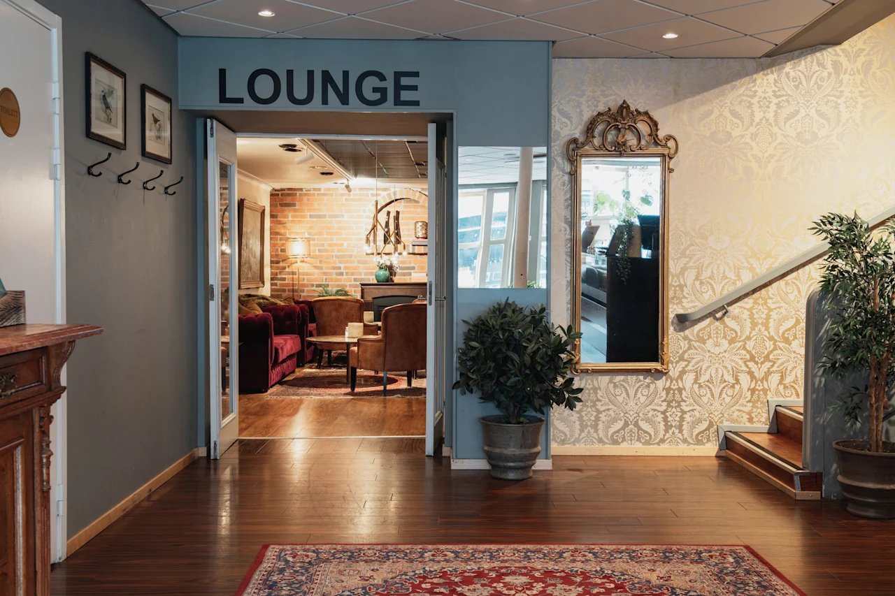 Ett inbjudande loungeområde med bekväma sittplatser, synligt genom en öppen dörröppning märkt LOUNGE.