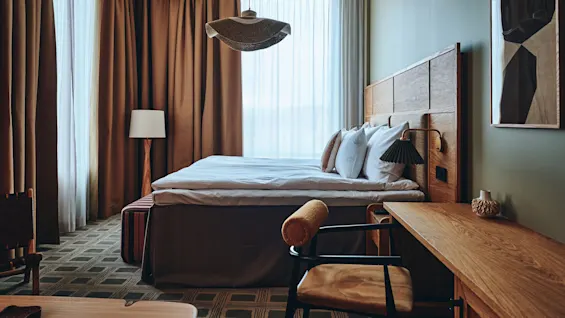 Et koselig hotellrom med en stor seng, tremøbler og varm belysning, som inviterer til avslapning og komfort.