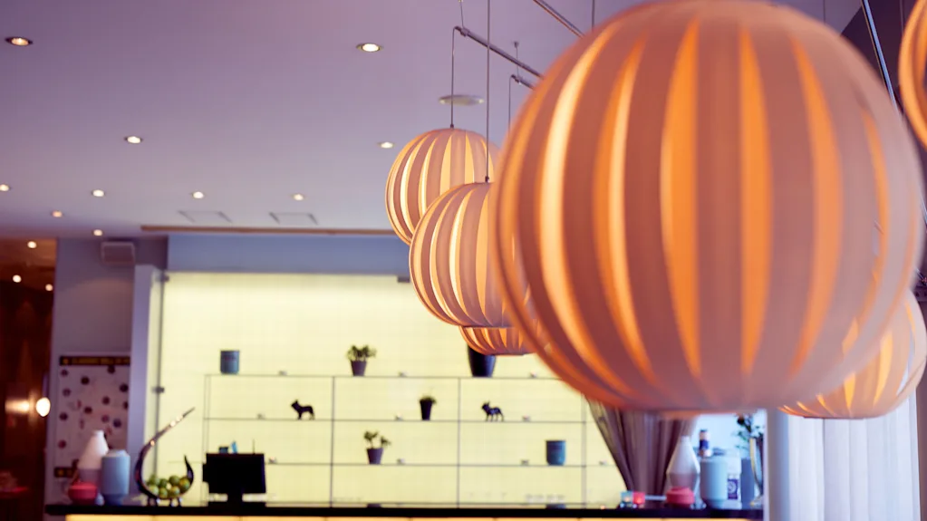 Moderne pendellamper dominerer forgrunden i et blødt belyst, stilfuldt indendørs rum.