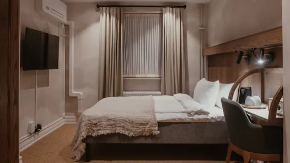 Home Hotel Baltzar - Compact Cabin: A cozy hotel room featuring a comfortable bed, a small desk, and a wall-mounted TV.