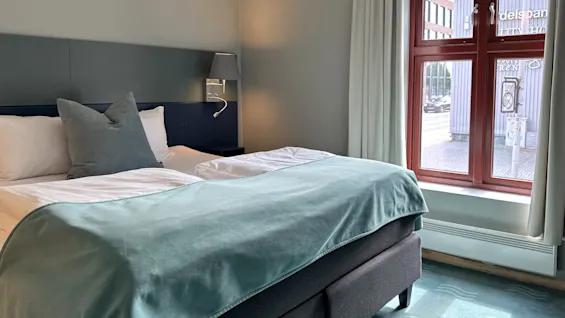 Viihtyisä hotellihuone, jossa mukava sänky ja ikkuna kadulle päin.