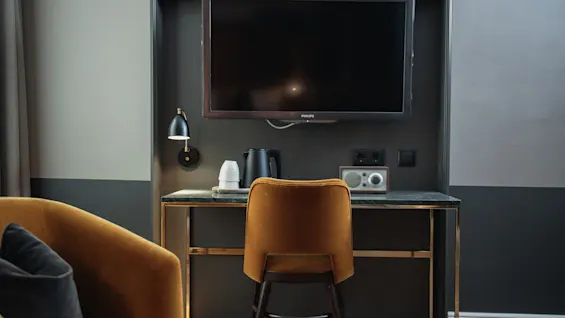 Et hyggeligt hotelværelses skrivebordsområde med et tv, en elkedel til varme drikke og en radio, perfekt til afslapning eller arbejde.