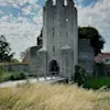 Ett historiskt stentorn och bro längs Visby ringmur under en solig dag.