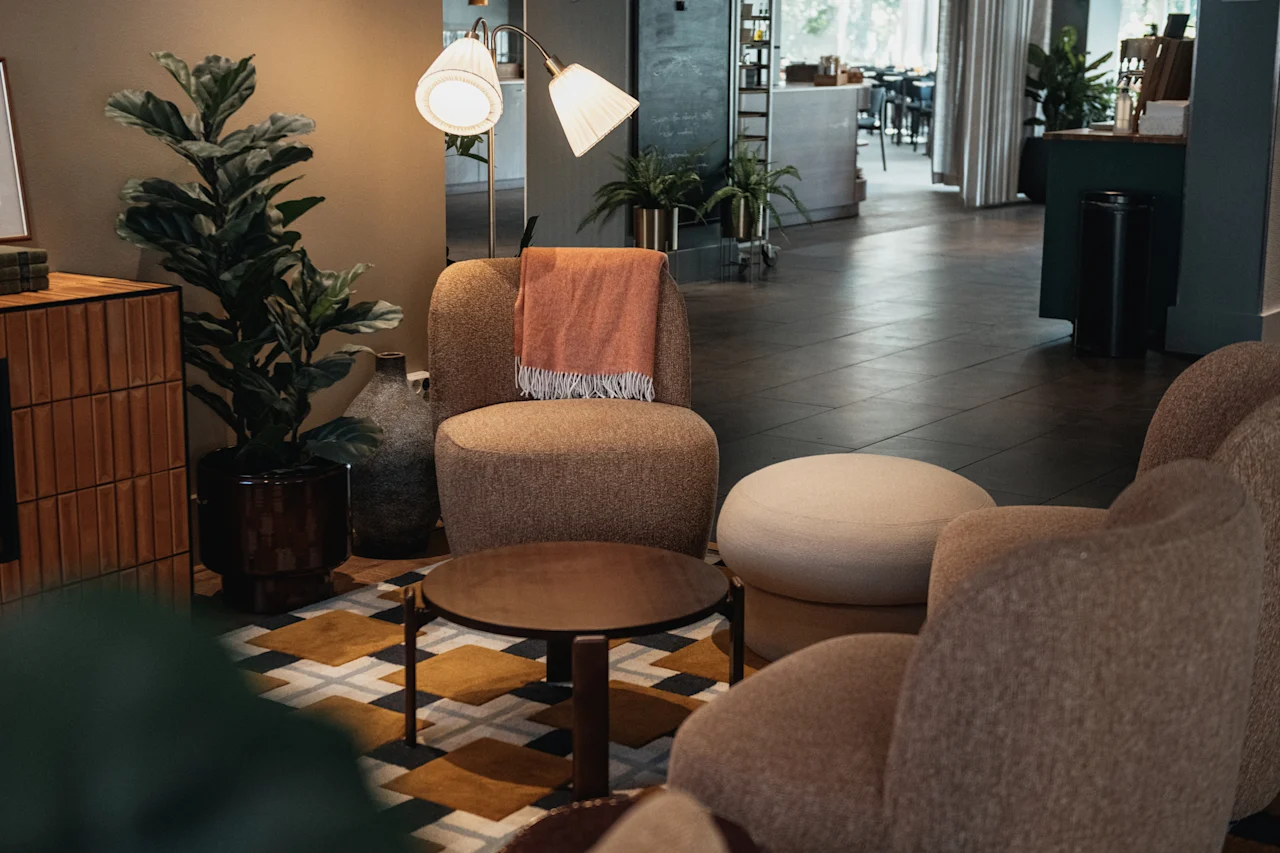 En mysig hotellounge med bekväma sittplatser, ett soffbord och en stor växt, som inbjuder gästerna att koppla av.
