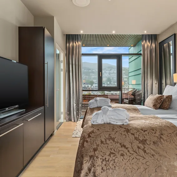 Et komfortabelt hotellrom på Quality Hotel Ulstein med to senger, en TV og en balkong som tilbyr en naturskjønn utsikt over byen.