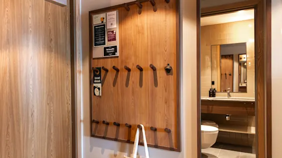 Hotel room entrance at Quality Hotel The Book in Gothenburg, with a wooden panel, hooks, notices, and a view of the bathroom.