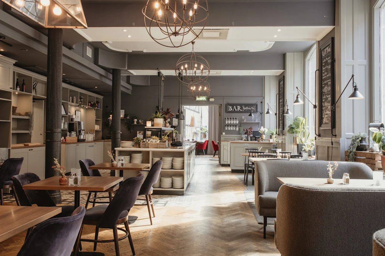 Et elegant restaurant- eller barinteriør med tregulv, varierte sitteplasser og en velutstyrt bar. Et skilt leser BAR.